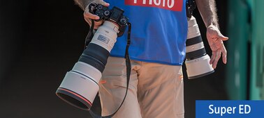 Slika upotrebe koja prikazuje fotografa kako nosi dva fotoaparata s telefoto objektivima