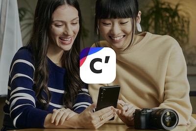 Slika dviju žena koje gledaju u pametni telefon s dodanim logotipom usluge Creators’ Cloud