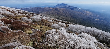Prostrani krajolik prikazuje niz planina. Planina u prvom planu prekrivena je snijegom i nalazi se u fokusu